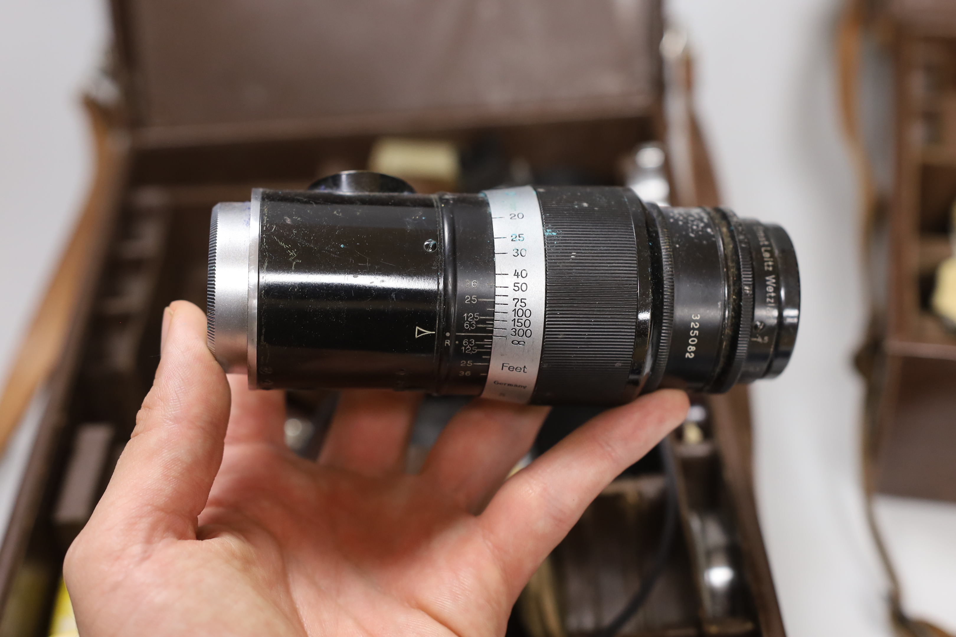 A collection of Leica etc camera accessories, including Leica film canisters, Leitz Elmer lenses and accessories, two Leica leather cases containing accessories in fitted compartments, three hardback Leica manuals, bookl